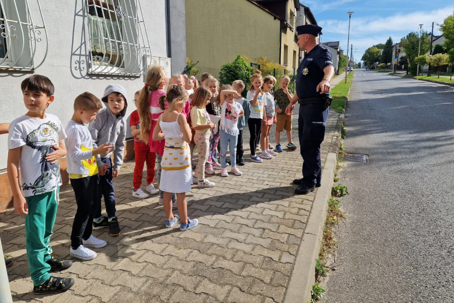 Umundurowany policjant prowadzi spotkanie z dziećmi.