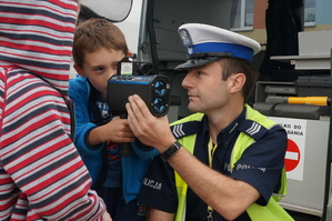 Policjant z wydziału ruchu drogowego prezentuję uczniom urządzenie do pomiaru prędkości