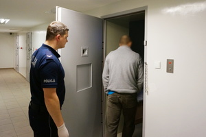Policjant wprowadza do celi zatrzymanego włamywacza