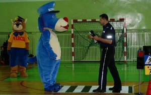 Policjant z maskotką Sznupka na przejściu dla pieszych