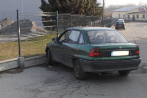 Miejsce kolizji. Na pierwszym planie tył zielonego opla astry, który uderzył w metalowe ogrodzenie.