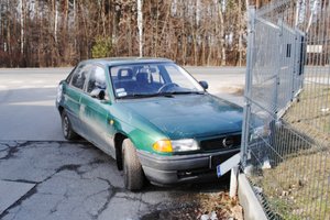 Miejsce kolizji. Na pierwszym planie przód zielonego opla astry, który uderzył w metalowe ogrodzenie z betonową podmurówką.