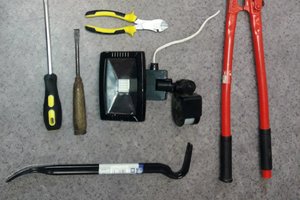 Odzyskana lampa z czujnikiem ruchu i narzędzia którymi posługiwał się włamywacz, łom i śrubokręty