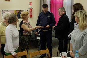Przedstawicielka seniorów wręcza policjantowi podziękowanie.