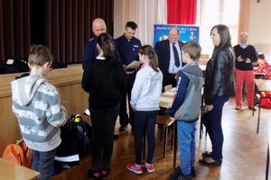 Dwaj policjanci wręczają dyplomy najlepszym zawodnikom turnieju.