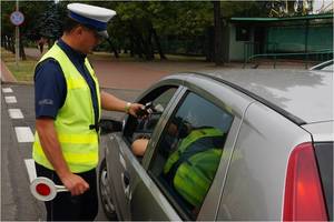 Policjant z wydziału ruchu drogowego sprawdza stan trzeźwości kierowcy.
