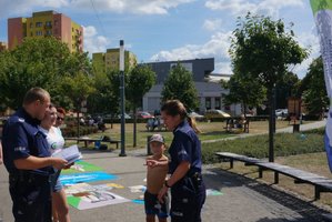 Policjantka i Policjant wraz z przedstawicielką Centrum Rozwoju Lokalnego przekazują chłopcu materiały informacyjne - ulotkę i kolorowankę.