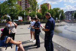 Policjantka, Policjant i przedstawicielka Centrum Rozwoju Lokalnego przekazują dwóm paniom materiay informacyjne - ulotki i kolorowankę dla dziecka.