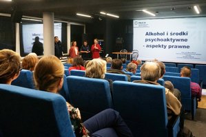 Uczestnicy spotkania siedzący na sali kinowej. Na ekranie widnieje napis: Alkohol i środki psychoaktywne – aspekty prawne.