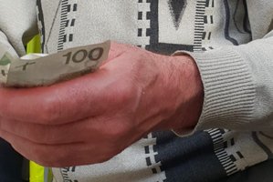 Dłoń pijanego kierowcy z banknotami, które próbował wręczyć policjantom.