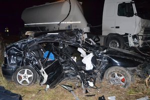 Rozbity Seat Leon. Na drugim planie ciężarówka z cysterną. W tle policjant.