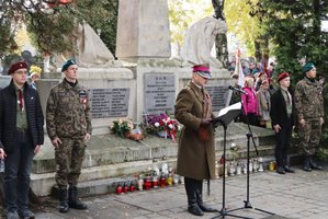 Umundurowany żołnierz czyta apel poległych przed Pomnikiem Niepodległości.