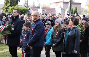 Delegacje z kwiatami stojące w kolejce przed Pomnikiem Niepodległości.
