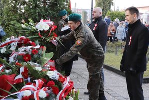 Uczeń szkoły mundurowej składa kwiaty przed Pomnikiem Niepodległości.