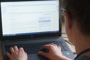 Widoczne dłonie osoby piszącej na klawiaturze laptopa.