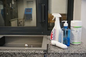 Środki ochronne - płyny do dezynfekcji w plastikowych butelkach, termometr bezdotykowy, chusteczki dezynfekujące w plastikowym, białym pojemniku.