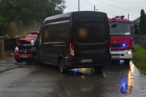 Widoczne dwa samochody, które się zderzyły brązowy cięzarowy i czerwony straży pożarnej. Widoczny także wóz strażacki.