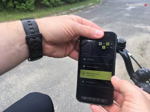 Widoczny trzymany w rękach smartfon z uruchomioną palikacją.