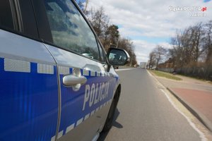 Częściowo widoczny bok jadącego radiowozu, z napisem POLICJA.