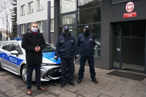 Obok siebie stoją od lewej: Prezydent Zawiercia Łukasz Konarski, Komendant Powiatowy Policji w Zawierciu inspektor Jacek Kurdybelski, Pierwszy Zastępca Komendanta Powiatowego Policji mł. insp. Arkadiusz Miśta. Za nimi widoczny oznakowany radiowóz.