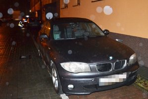 Na zdjęciu z prawej strony widoczne zaparkowane dwa samochody osbowe. W tle widoczny radiowóz oraz policjant wykonujący czynności.