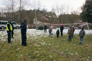 Na zdjęciu widoczni policjanci, którzy prowadzą prelekcję dla stojących przed nimi dzieci.