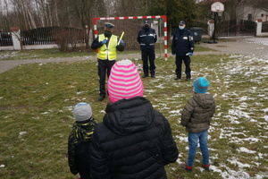 Na zdjęciu widoczni policjanci, którzy prowadzą prelekcję dla stojących przed nimi dzieci.