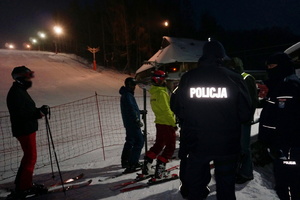 Na zdjęciu widoczni policjanci i narciarze. W tle widoczny stok.