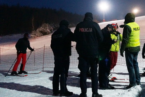 Na zdjęciu widoczni policjanci i narciarze. W tle widoczny stok.