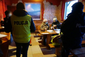 Na zdjęciu widoczni w pomieszczeniu policjanci, a także przedstawicielki Powiatowej Stacji Sanitarno - Epidemiologicznej, które przeglądają dokumenty.