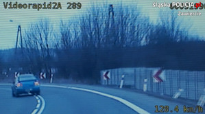 Stop klatka z wideorejestratora, na której widać samochód osobowy, który przekroczył linię ciągłą i jedzie po przeciwnym pasie ruchu.