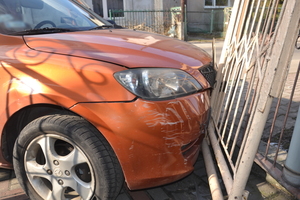 Na zdjęciu widoczny przód samochodu, który wjechał w ogrodzenie posesji.