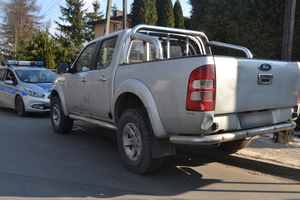 Na zdjęciu wiodczny samochód typu pickup, przed którym stoi oznakowany radiowóz.