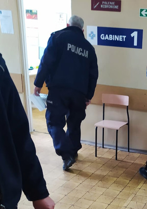 Umundurowany policjant wchodzący do gabinetu lekarskiego.