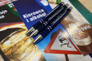 Na zdjęciu widoczne trzy długopisy, leżące na ulotkach dotyczących problemów alkoholowych