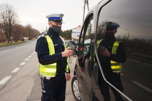 Na zdjęciu widoczny umundurowany policjant podczas badania stanu trzeźwości kierowcy samochodu.