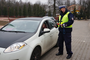 Na zdjęciu widoczny umundurowany policjant podczas badania stanu trzeźwości kierowcy samochodu.