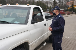 Na zdjęciu widoczny umundurowany policjant rozmawiający z kierowcą samochodu.