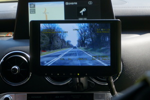 Zdjęcie z wnętrza radiowozu. Widoczny ekrean rejestratora, a także jadące przed radiowozem pojazdy.