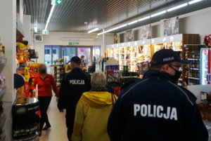Umundurowani policjanci kontrolują w placówkach handlowych przestrzeganie obowiązku zasłaniania ust i nosa