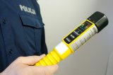 Na zdjęciu widoczny częściowo umundurowany policjant trzymający w ręku urządzenie do badania stanu trzeźwości Alcoblow.