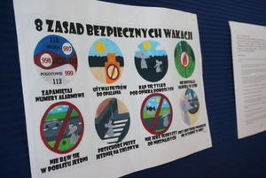Na zdjęciu widoczna karta z grafikami obrazującymi 8 zasad bezpiecznych wakacji.