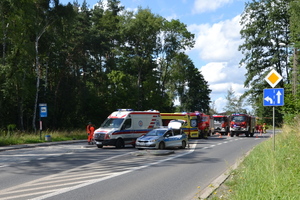 Na zdjęciu widczoczne miejsce wypadku drogowego i pracujące służby. Widoczne karetki pogotowia, radiowóz i wozy strażackie.