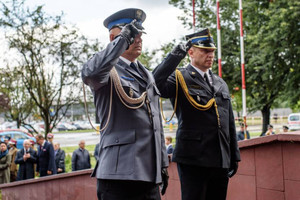 Zdjęcie: Urząd Miejski w Zawierciu. Komendant Powiatowy Policji w Zawierciu wraz z Komendantem Powiatowej Państowwej Straży Pożarnej w Zawierciu oddają honor salutując przed Pomnikiem Ofiar Hitleryzmu i Stalinizmu w Zawierciu.
