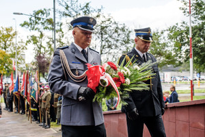 Zdjęcie: Urząd Miejski w Zawierciu. Komendant Powiatowy Policji w Zawierciu wraz z Komendantem Powiatowej Państowwej Straży Pożarnej w Zawierciu składają kwiaty przed Pomnikiem Ofiar Hitleryzmu i Stalinizmu w Zawierciu.