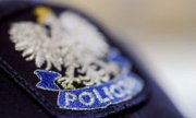 Na zdjęciu widoczna częściowo policyjna czapka z naszywką, na której jest orzeł w koronie i pod nim napis POLICJA.