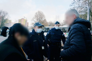 Na zdjęciu widoczni umundurowaniu policjanci rozmawiający z kobietą i mężczyzną.