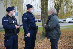 Na zdjęciu widoczni umundurowaniu policjanci rozmawiający z mężczyzną.