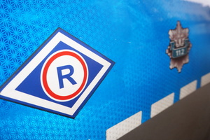 Na zdjęciu widoczne częściowo oznakowanie radiowozu: symbol ruchu drogowego i policyjna giwazda