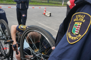 Na zdjęciu widoczna naszywka na koszuli strażnika miejskiego. W tle drugi strażnik znakuje rower.